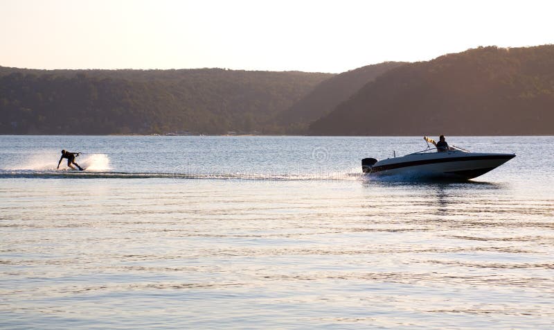 Atardecer acuoso practicante de wakeboard aerosoles Agua para rápidamente velocidad un barco en,,,.