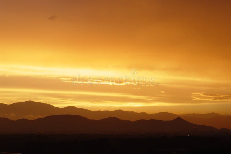 Sunset with orange clouds highlighted and dark mountain and ground. Sunset with orange clouds highlighted and dark mountain and ground