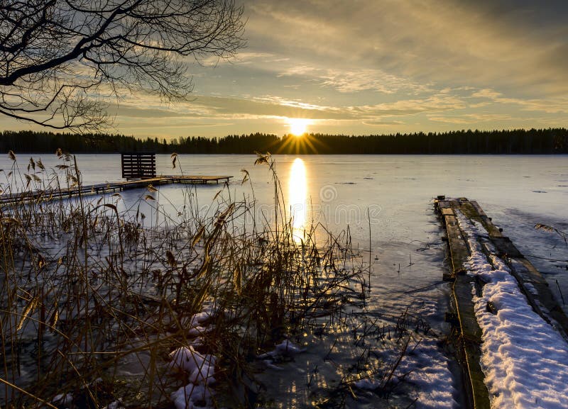 Sunset on a cold winter evening in the Russian province on the background of a frozen lake and pier. Sunset on a cold winter evening in the Russian province on the background of a frozen lake and pier