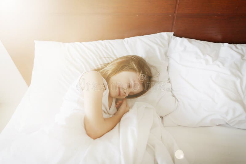 Sunshine portrait of sleeping kid girl at white bed