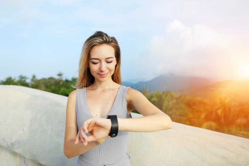 Sunshine portrait of young blonde woman using smartwatch, mountains in background, Thailand. royalty free stock photography Sunshine portrait of young blonde woman using smartwatch, mountains in background, Thailand. royalty free stock photography