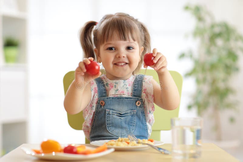 Sunt ungenäringbegrepp Gladlynt litet barnflickasammanträde på tabellen med plattan av sallad, grönsaker, pasta i rum royaltyfri fotografi Sunt ungenäringbegrepp Gladlynt litet barnflickasammanträde på tabellen med plattan av sallad, grönsaker, pasta i rum royaltyfri fotografi