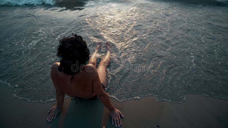 Suntan beach woman tanning legs relaxing swimming in ocean water with sunset sun drawing in sunscreen lotion sunblock cream