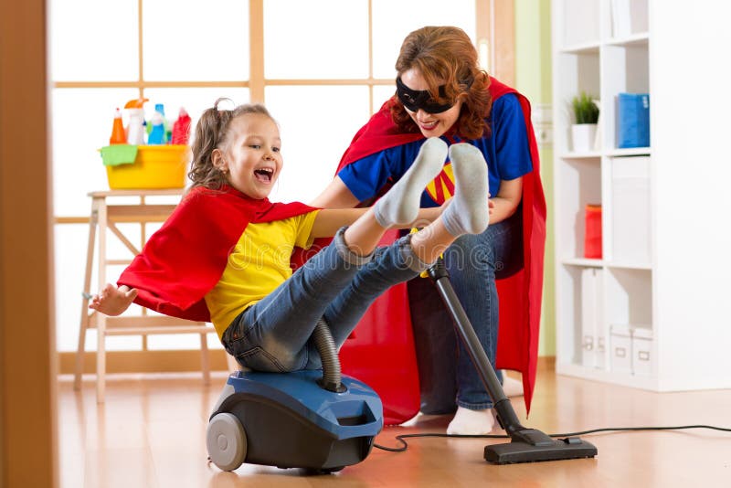 Super hero kid flying on vacuum cleaner. Mother and child daughter cleaning the room and have a fun