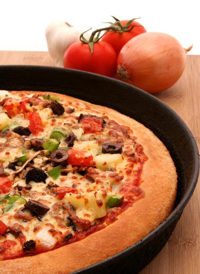 A supreme pizza in a pan with mixed vegetables. A supreme pizza in a pan with mixed vegetables