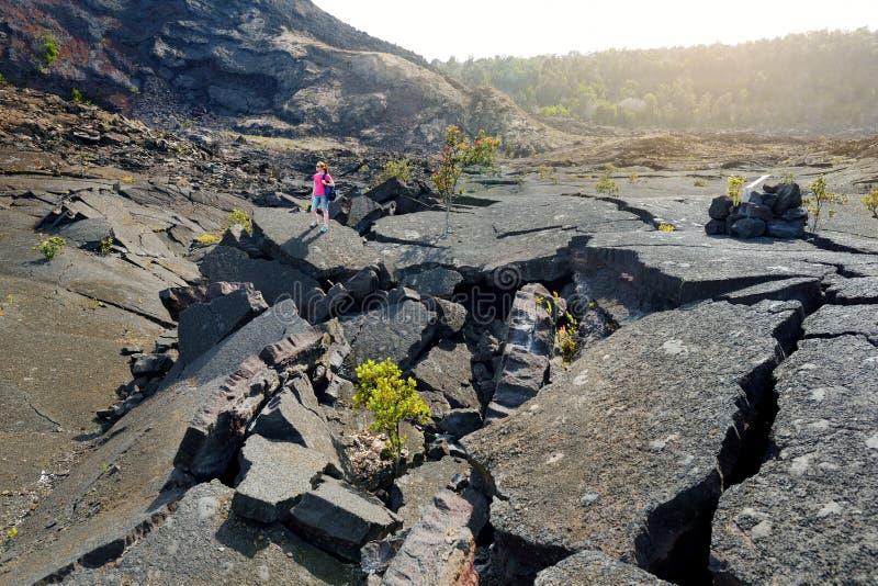 Superficie de exploración del turista femenino joven del cráter del volcán de Kilauea Iki con la roca de la lava que desmenuza en