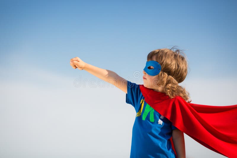 Superhéroe un nino contra cielo azul.