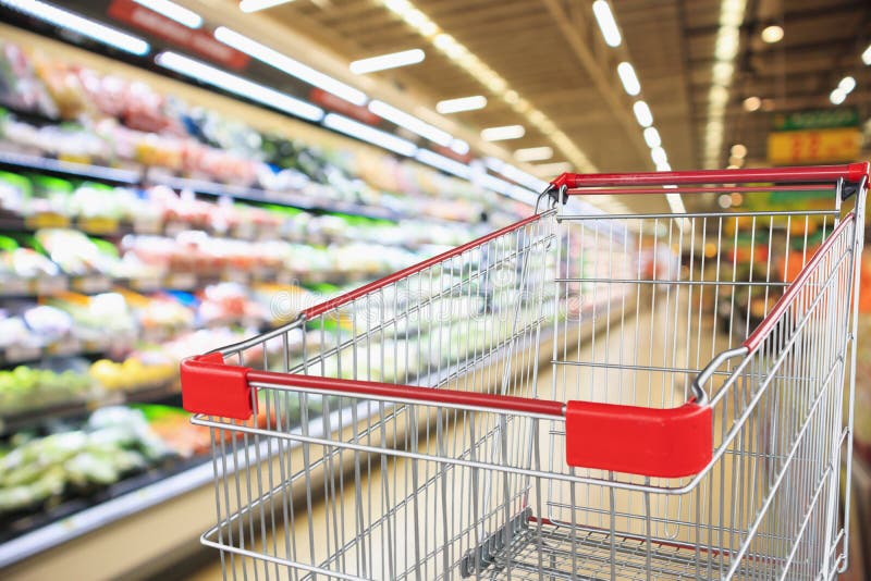 Supermarket grocery store with fruit and vegetable shelves interior defocused background with empty shopping cart