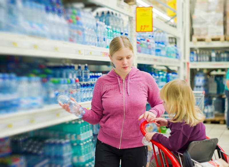 Mother and daughter in water section in supermarket. Mother and daughter in water section in supermarket