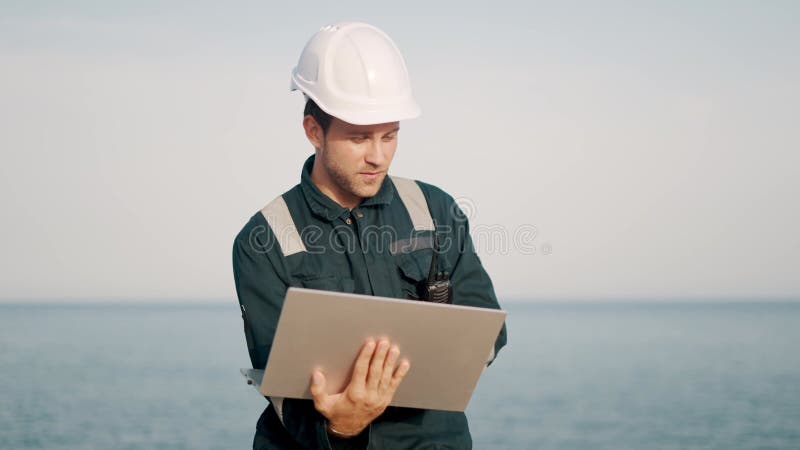 Supervisor del inspector de puertos concentrado trabajando en el ordenador portátil en el terminal de buques