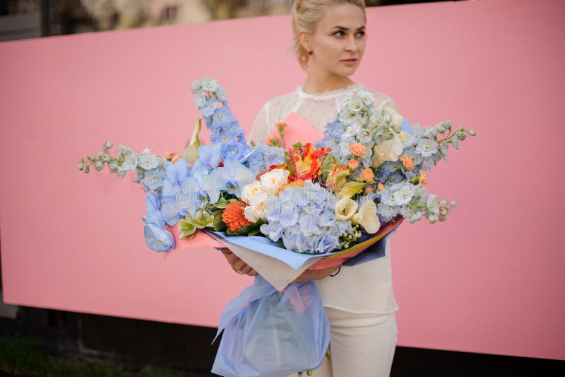 Support de fille avec le grand bouquet des fleurs bleues photos stock Support de fille avec le grand bouquet des fleurs bleues photos stock
