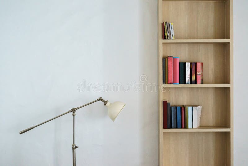 Support de lampe en métal et étagère en bois avec des livres. Support de lampe en métal et étagère en bois avec les livres colorés sur le mur blanc