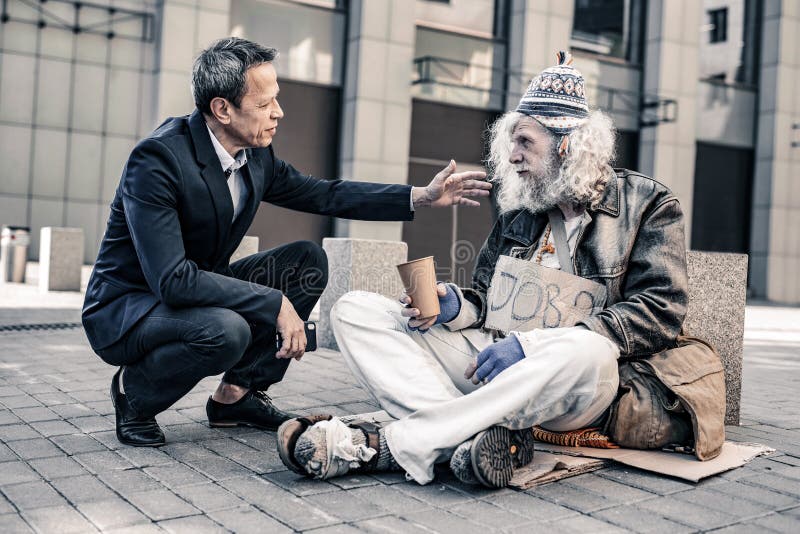 Helpful caring man in costume putting hand on shoulder of dirty homeless ro...