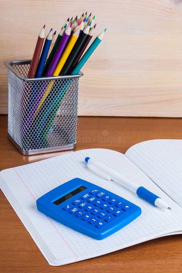 Sur le livre d'exercice dans une calculatrice et un stylo bleus menteur de cellules image stock Sur le livre d'exercice dans une calculatrice et un stylo bleus menteur de cellules image stock