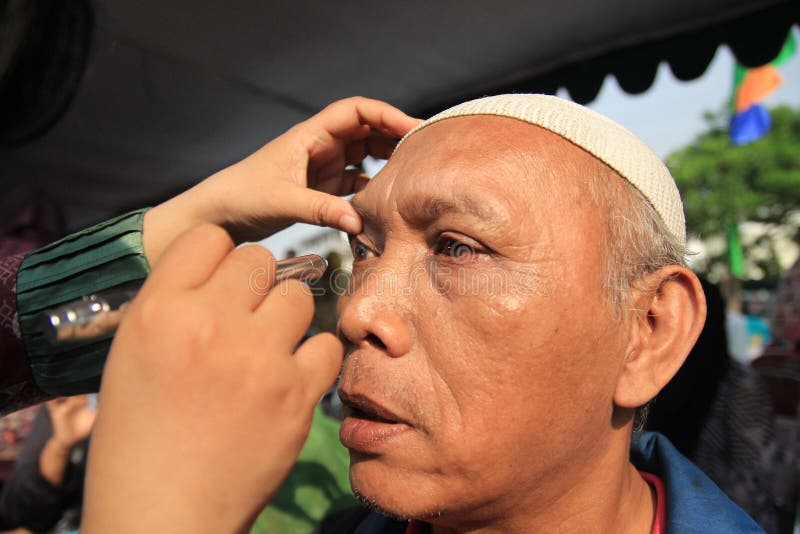 Surabaya indonesia, kan 21, 2014 en vård- arbetare kontrollerar patientens ögon royaltyfria bilder Surabaya indonesia, kan 21, 2014 en vård- arbetare kontrollerar patientens ögon royaltyfria bilder