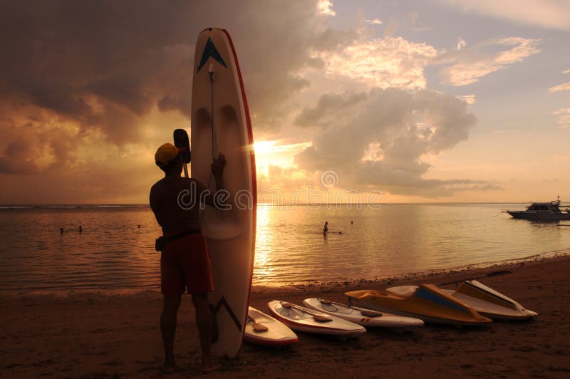 Surf boards line the beach decorating the rising sun on the coast of Sanur