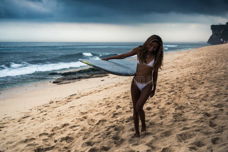 Surfboard нося женщины на пляже стоковое фото Surfboard нося женщины на пляже стоковое фото