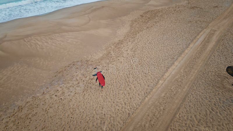 Surfbrett mit Sandstrand. dunkle Ozeanwellen, die beige Ufer spülen