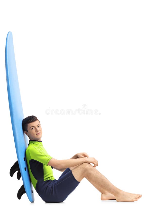 Surfer adolescent se penchant contre une planche de surf photo libre de droits Surfer adolescent se penchant contre une planche de surf photo libre de droits