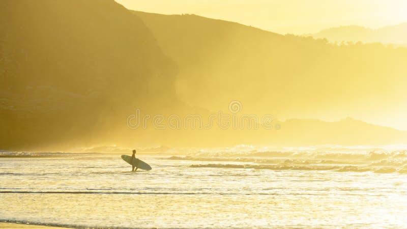 Surfer die water ingaan bij zonsondergang royalty-vrije stock afbeelding Surfer die water ingaan bij zonsondergang royalty-vrije stock afbeelding