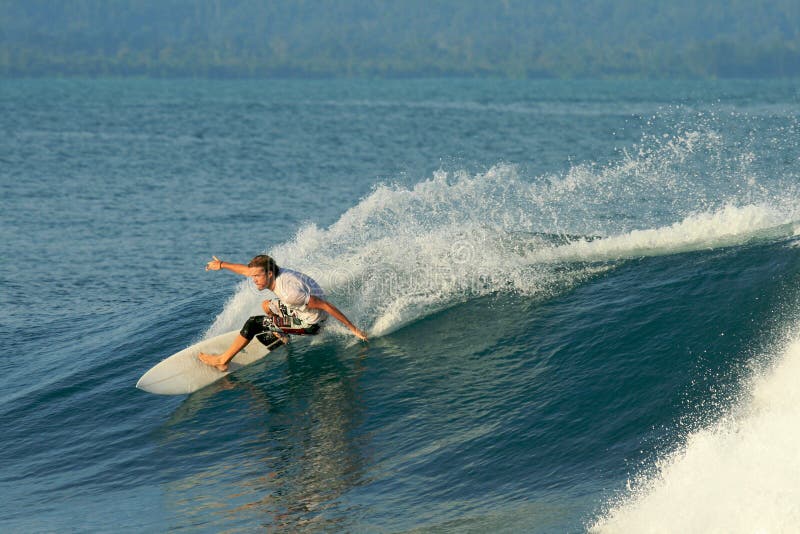 Surfer doing carving turn on smooth wave, Mentawai