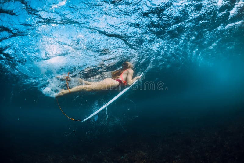 Surfer Girl in Bikini with Surfboard Dive Underwater and Wave Stock