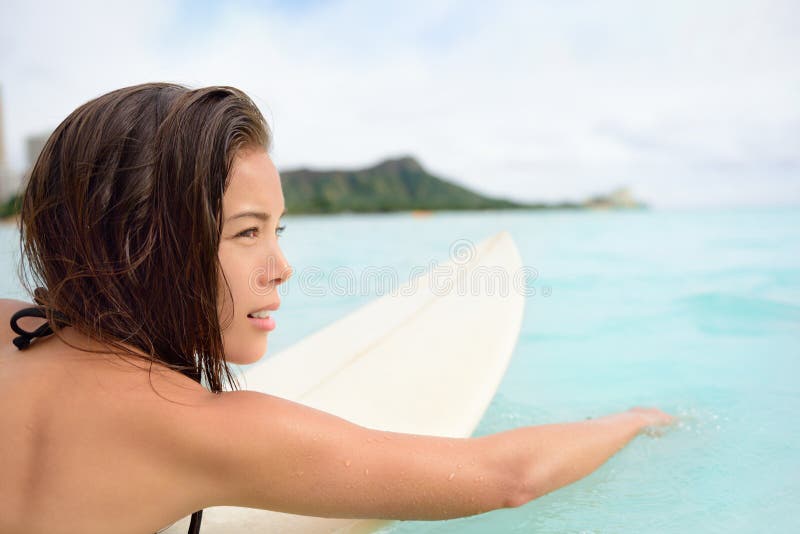 Surfer girl surfing paddeling on surfboard