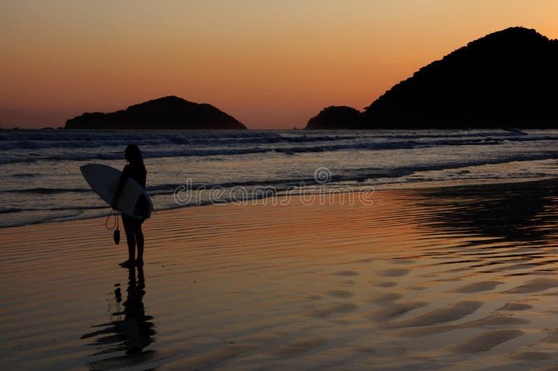 Surfer and Sunset Reflexion at a tropical beach