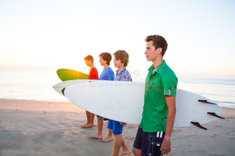 Surfer teenager boys walking at beach shore.