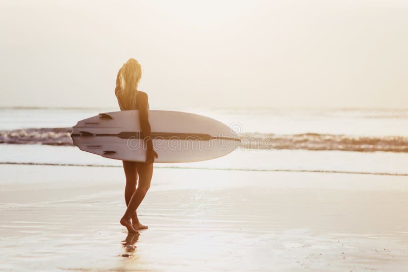 Surfermeisje surfen die oceaanstrandzonsondergang bekijken stock foto's Surfermeisje surfen die oceaanstrandzonsondergang bekijken stock foto's