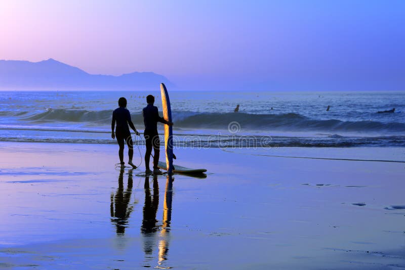 Surfers met zonsondergangbezinning over surfplank stock afbeelding Surfers met zonsondergangbezinning over surfplank stock afbeelding