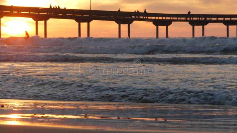 Surfers Surfing by Pier. Ocean Water Waves, People and Sky at Sunset ...