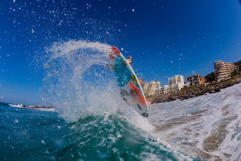 Flying surfboard and pro surfer Josh Redman punts are air turn maneuvers off the wave lip with fins and board colors and sea spray. Flying surfboard and pro surfer Josh Redman punts are air turn maneuvers off the wave lip with fins and board colors and sea spray.