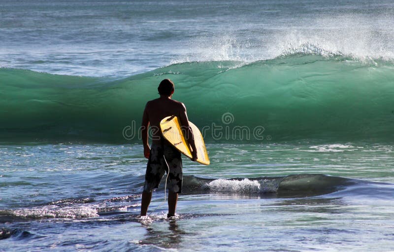 Man-surfer with board on a coastline. Bali. Indonesia. Man-surfer with board on a coastline. Bali. Indonesia