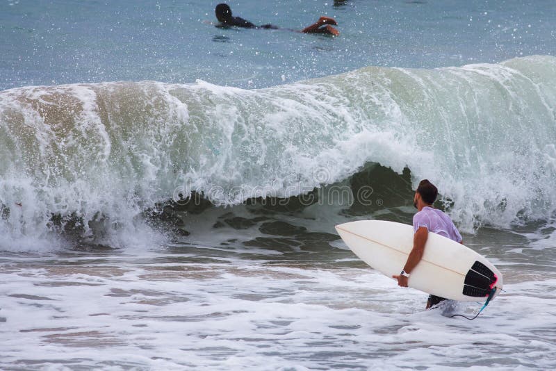 Surfista sull'oceano blu vicino a grande Wave, Bali, punto della spuma fotografia stock Surfista sull'oceano blu vicino a grande Wave, Bali, punto della spuma fotografia stock
