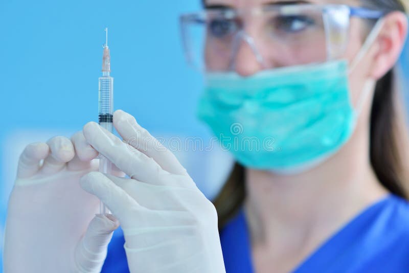 The Surgeon Dentist in Mask Holding Syringe for Injecting Anesthesia