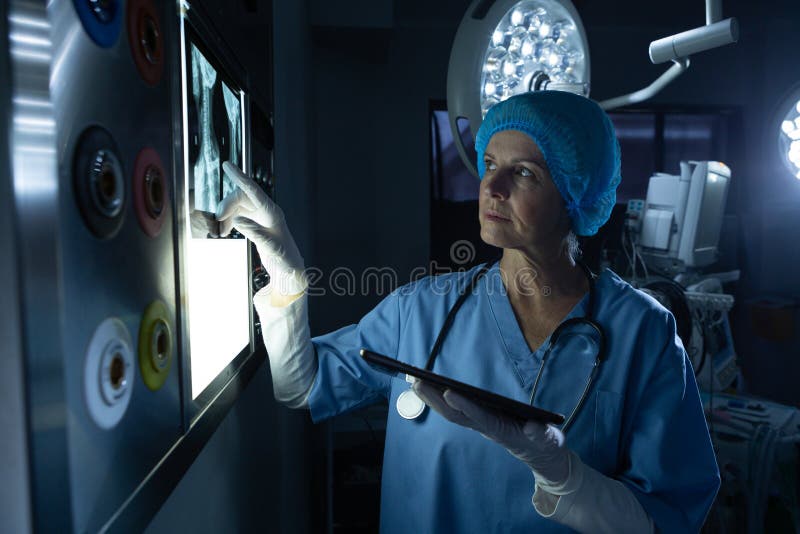 Surgeon examining x-ray on light box in operating room of hospital.