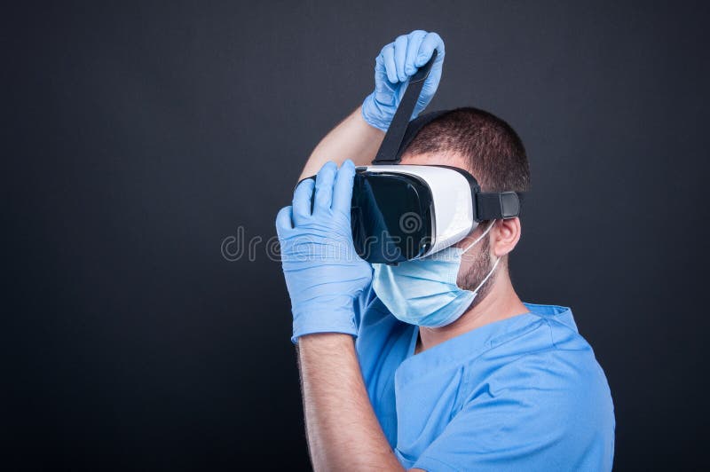 Surgeon wearing scrubs putting on vr goggles stock photos