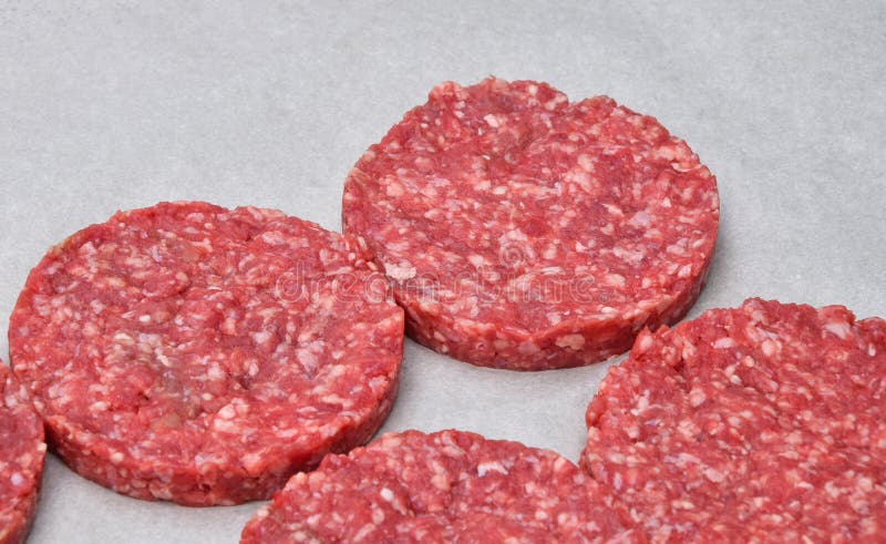 Surowego mięsa hamburgery dla hamburgerów na pergaminie zdjęcia stock Surowego mięsa hamburgery dla hamburgerów na pergaminie zdjęcia stock