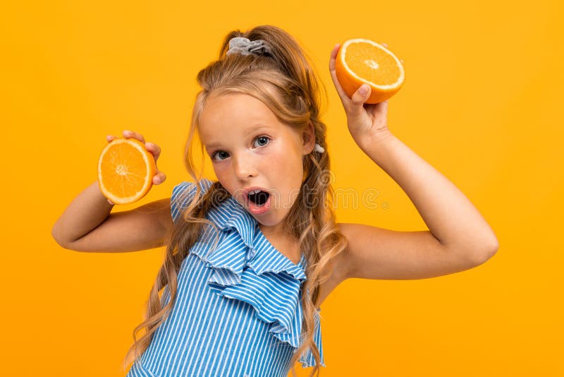 Surprised blond attractive girl with oranges on a yellow background