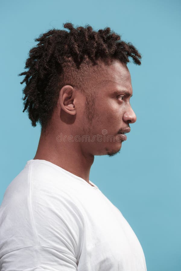 The surprised business Afro-American man standing and looking blue background. Profile view.