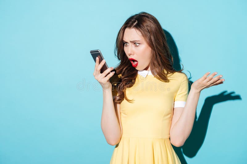 Surprised confused woman in dress looking at mobile phone royalty free stock photo Surprised confused woman in dress looking at mobile phone royalty free stock photo