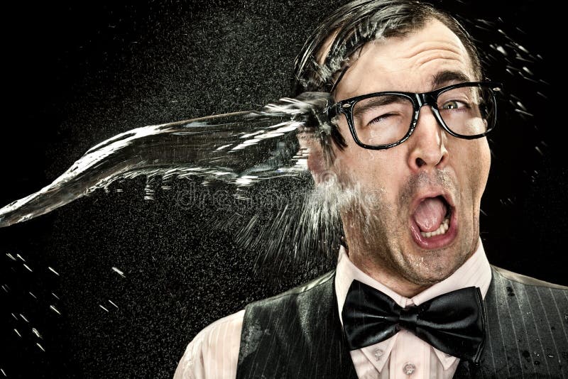 Surprised elegant nerd with glasses hit by cold water spray on black background.