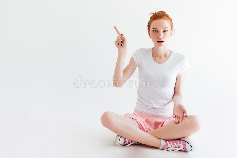 Surprised Ginger Girl Sitting On Floor And Looking At Camera Stock