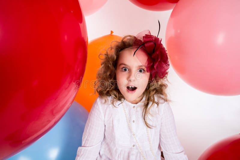 Surprised girl in a hat of the bow against the backdrop of a large bright airy rubber balls