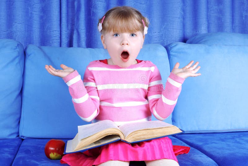 Surprised little girl with apple and book