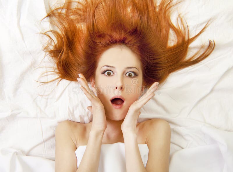 Surprised red-haired girl in bed