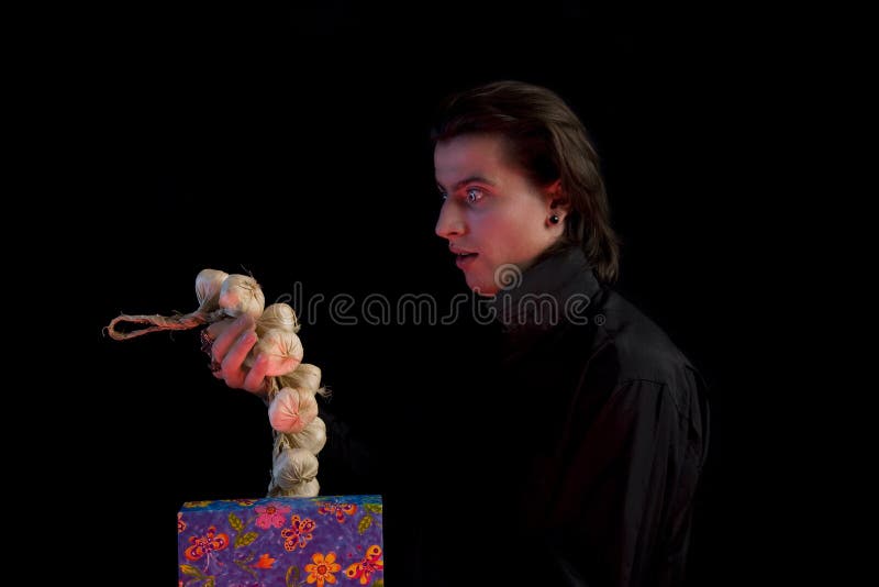 Surprised vampire with gift box taking out garlic stock photo