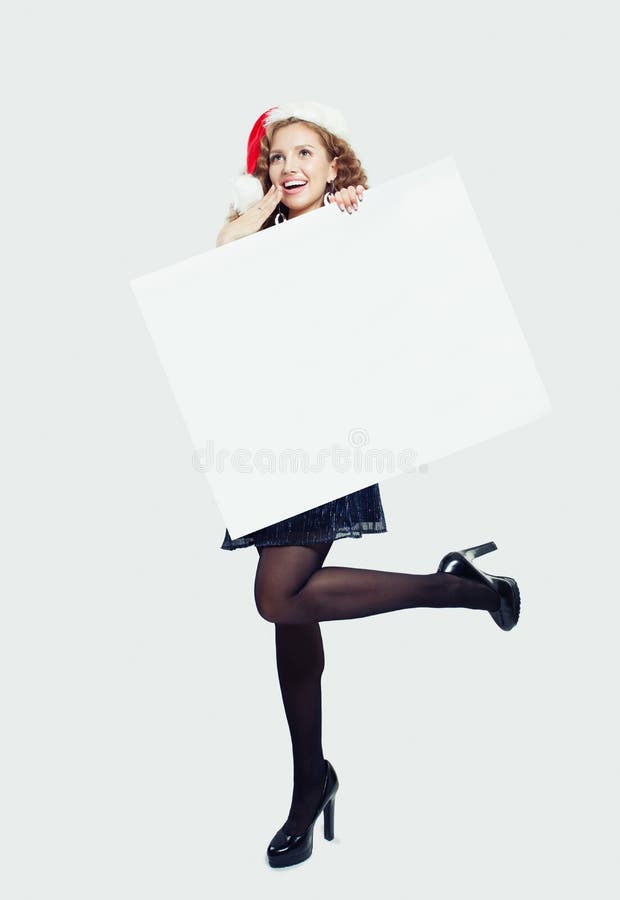 Surprised woman in black tights, high heels shoes and Santa hat holding empty paper card