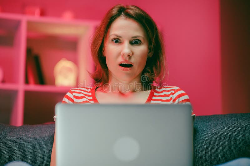 Surprised woman face looking at laptop screen. Close up of excited woman watch online news at computer. Portrait of